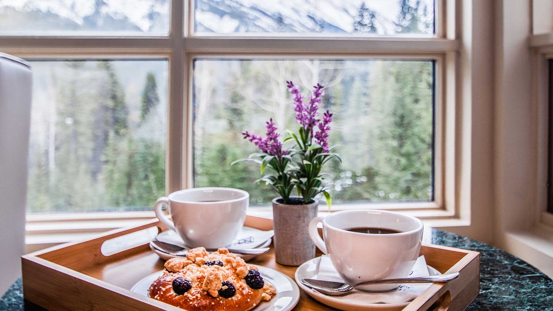 A breakfast tray with two coffee cups and a pastry