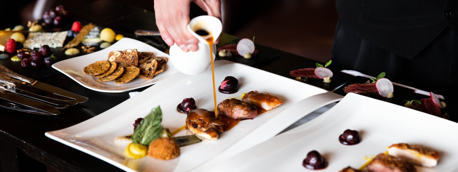 A person pouring liquid sauce on a food