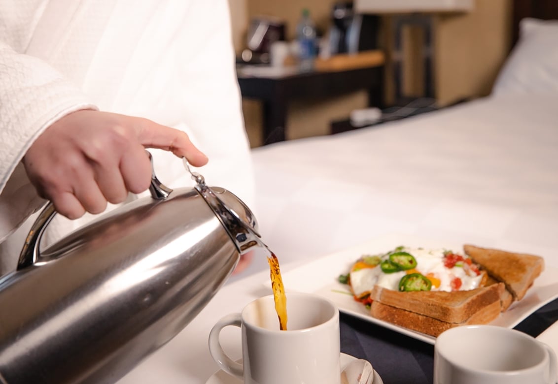 A person pouring coffee into a teacup