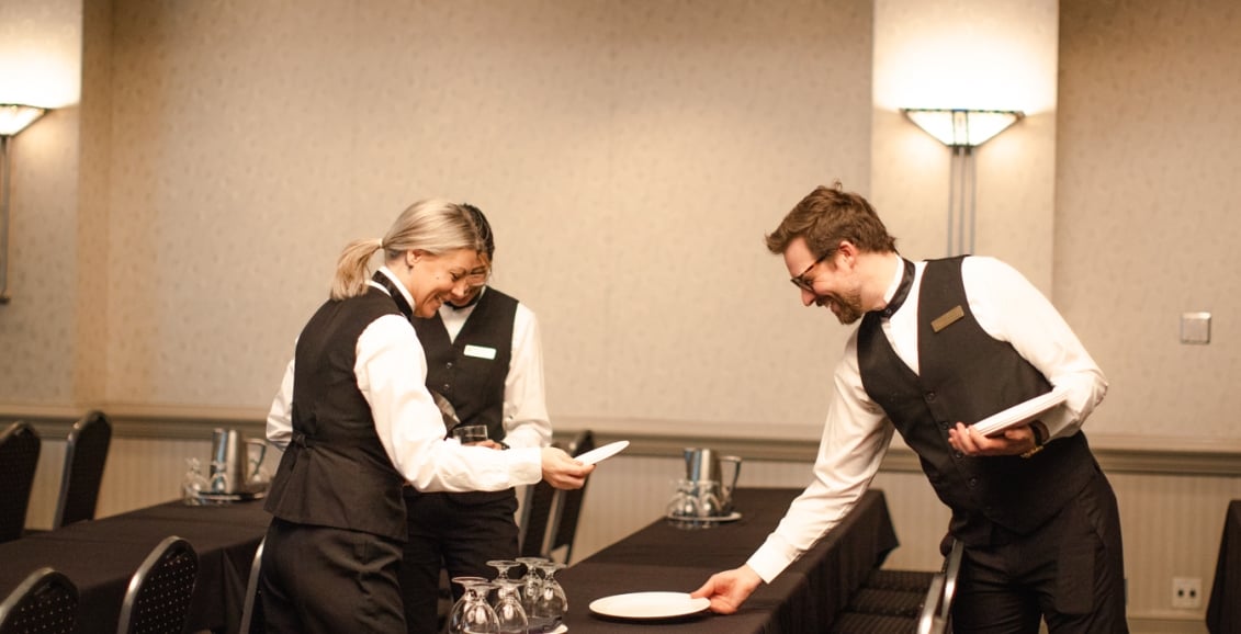 Three servers setting a table with plates