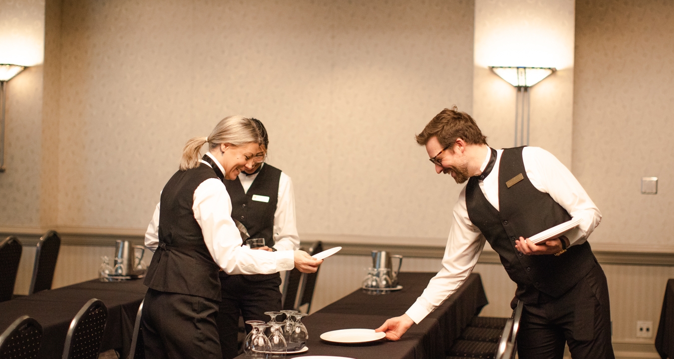 Three servers setting a table with plates