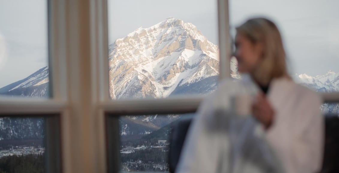 A woman sitting in a robe with her back to the mountains