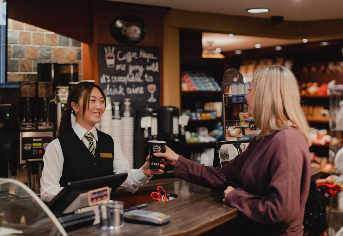 A barista handing a customer a drink