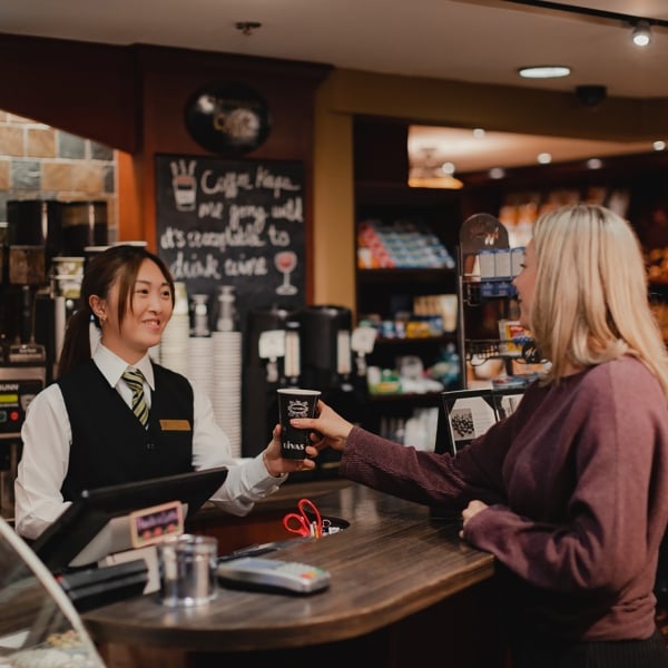 A barista giving a woman a cup