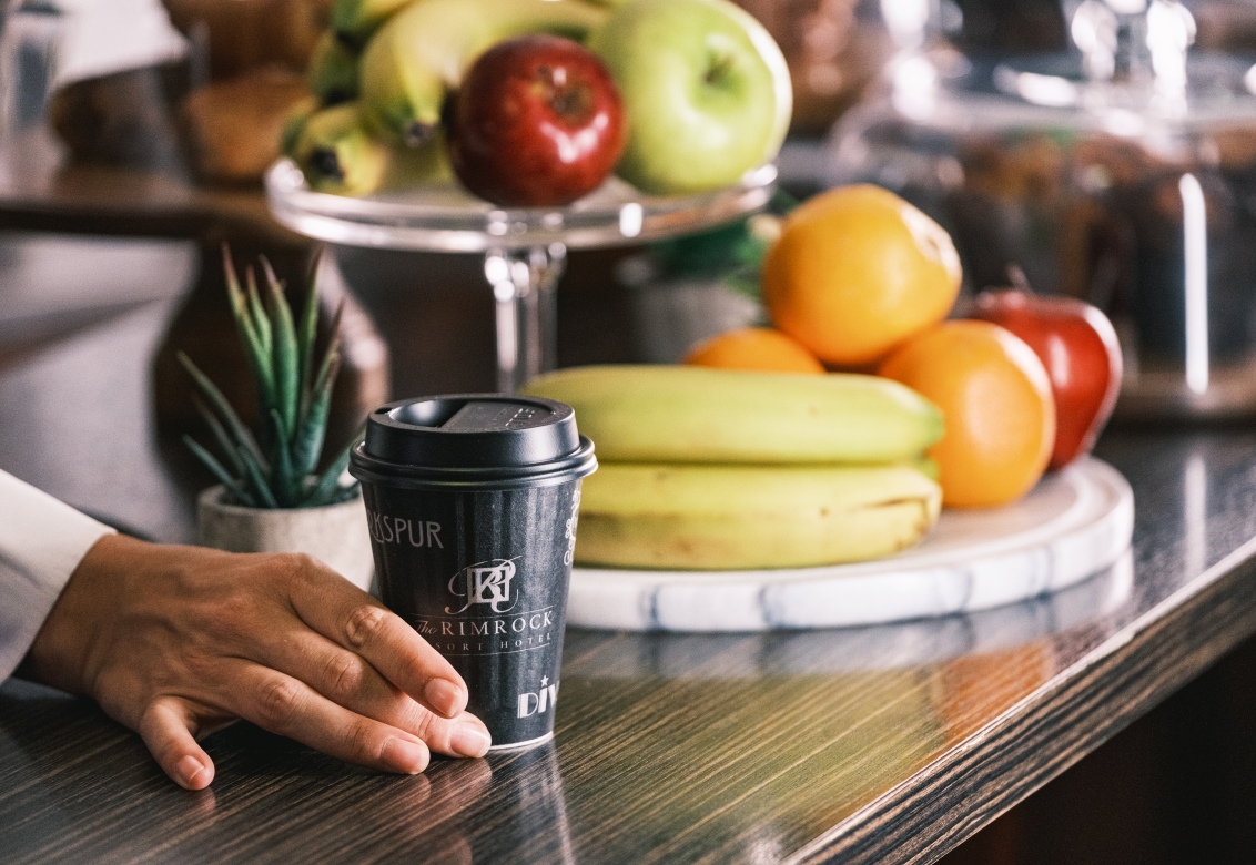 Coffee on counter with fruit in background