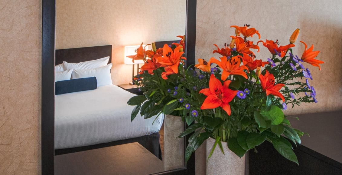 Flowers and a mirror facing a bed