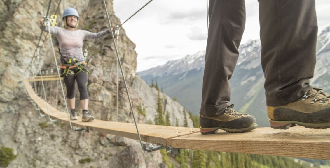 A couple walking across a thin bridge in Banff Alberta