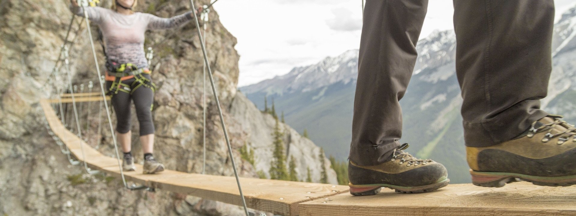 A couple walking across a thin bridge in Banff Alberta