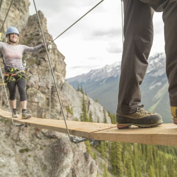 A couple walking across a thin bridge in Banff Alberta