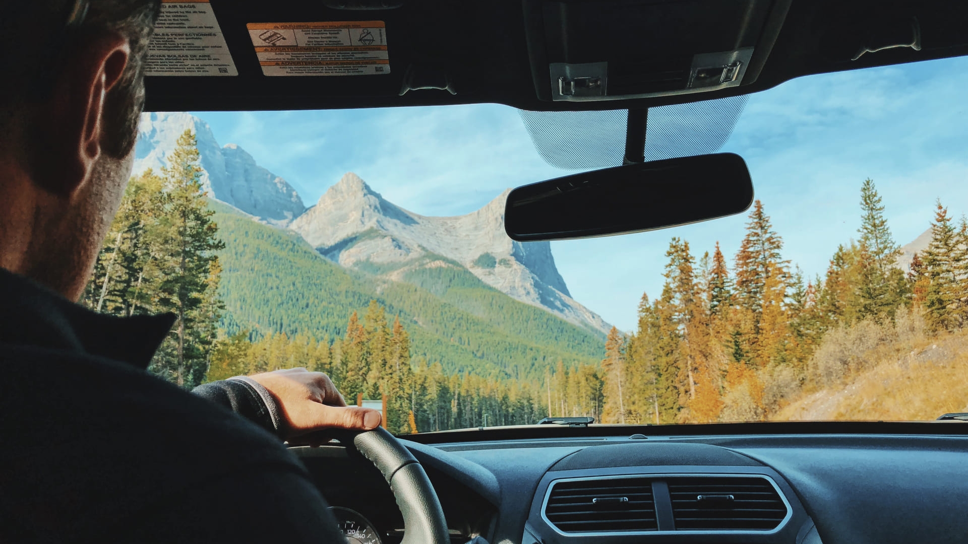 A man driving a car with mountains in view