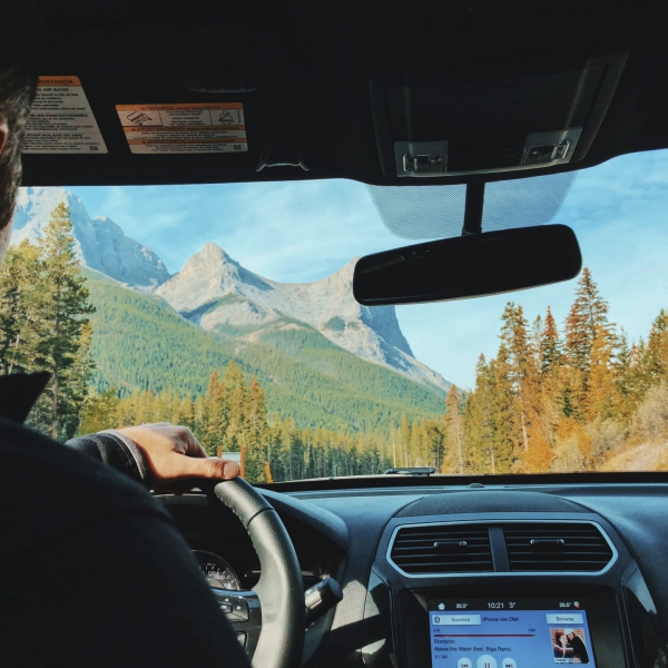 A man driving a car with mountains in view