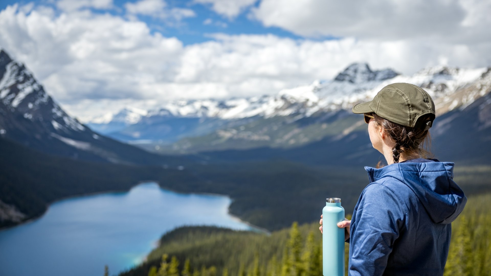 A woman holding a blue water bottle and overlooking the water