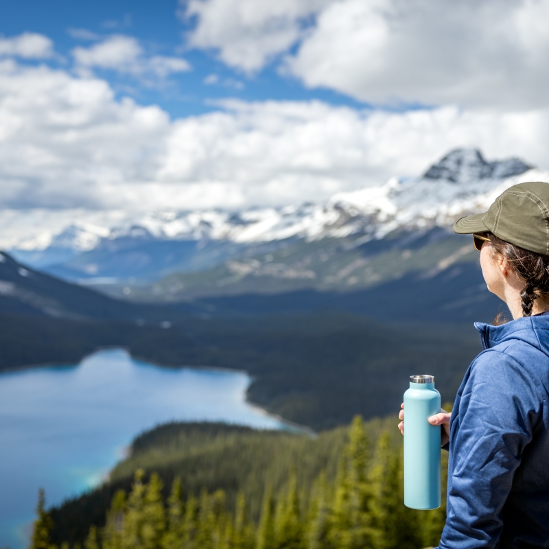 A woman holding a blue water bottle and overlooking the water