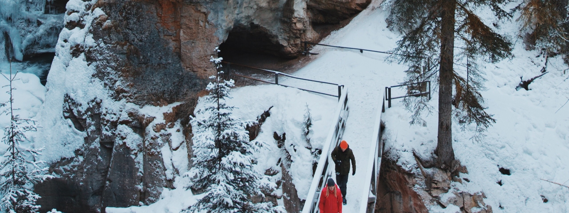 Two people walking on a bridge with snow