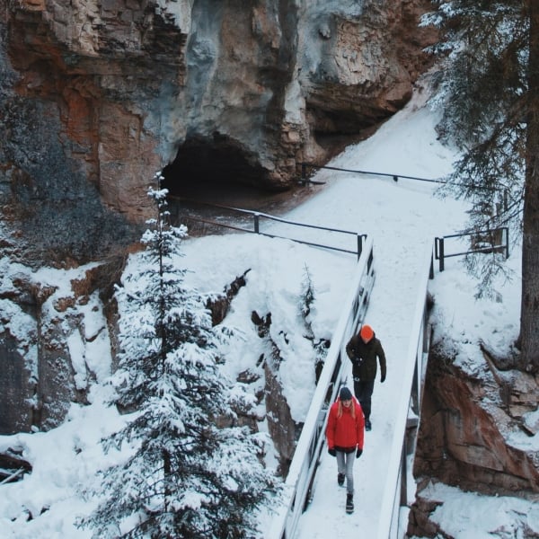 Two people walking on a bridge with snow