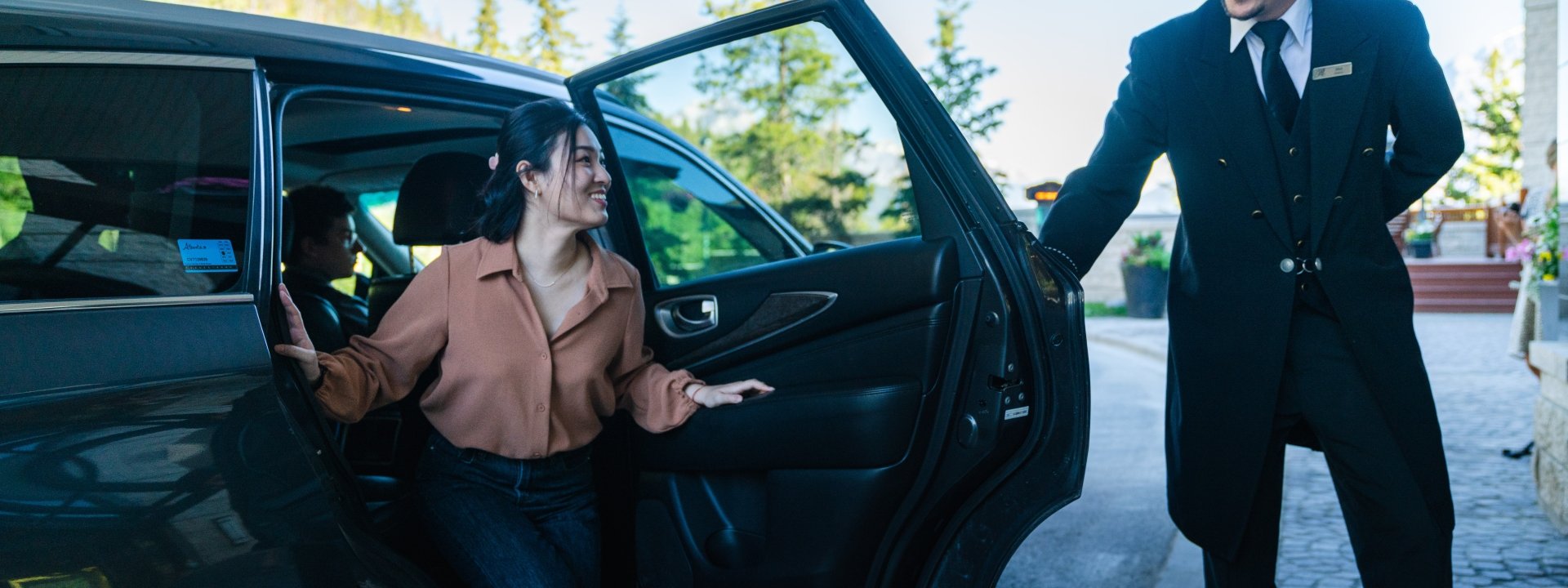 A man in a top hat opening the car door for a woman