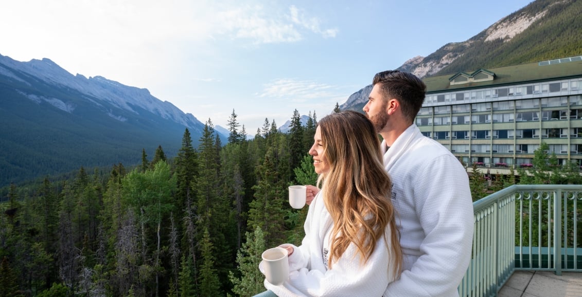 A couple standing on the balcony with coffee cups