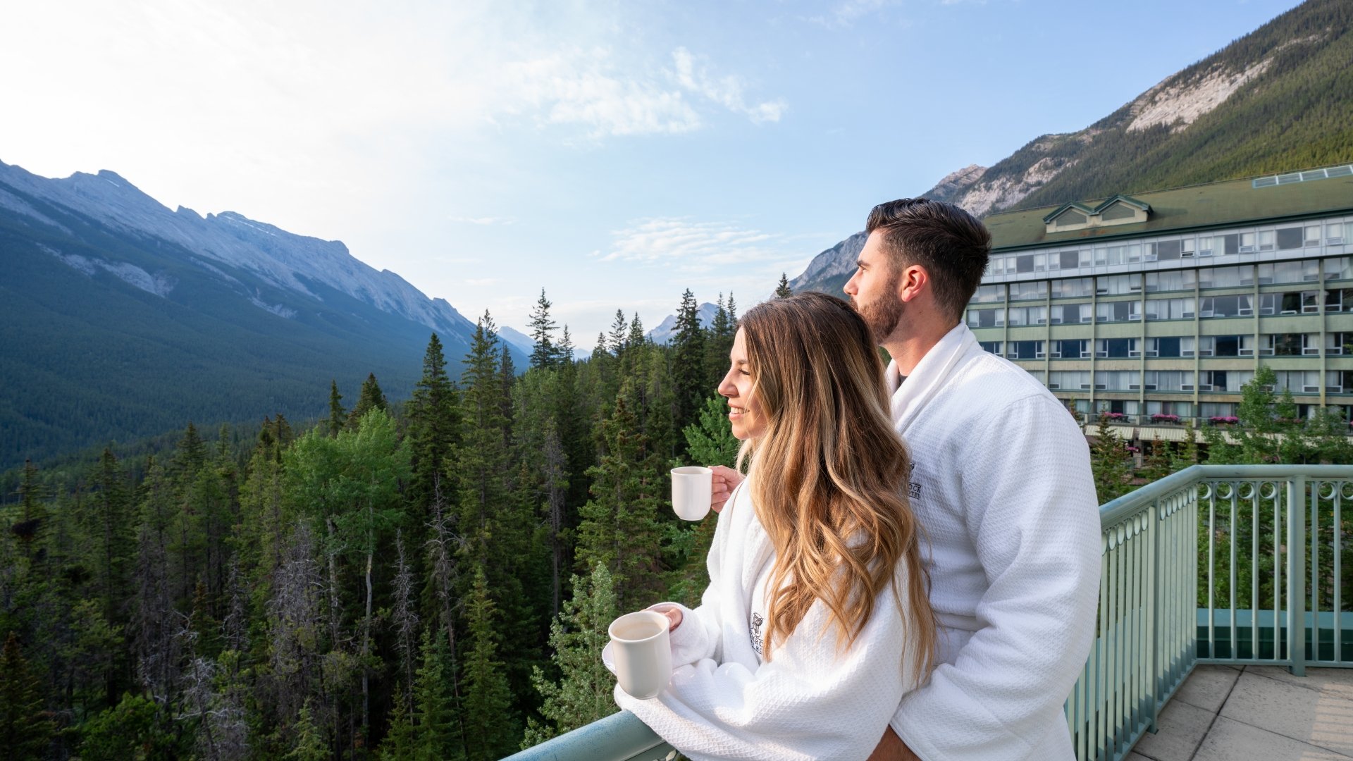 A couple standing on the balcony with coffee cups