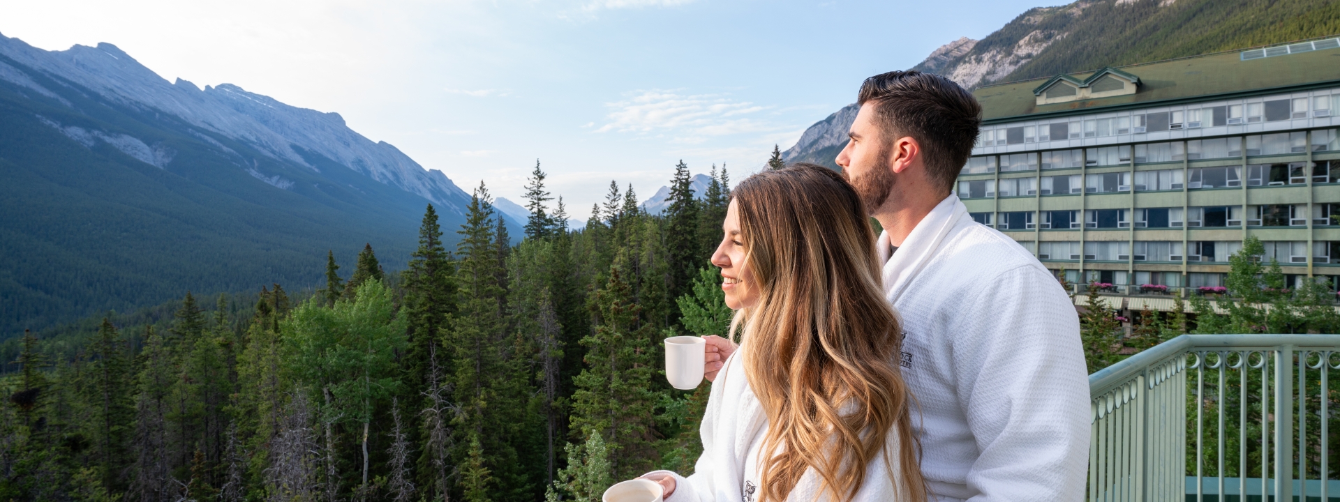 A couple standing on the balcony with coffee cups