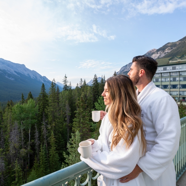 A couple standing on the balcony with coffee cups