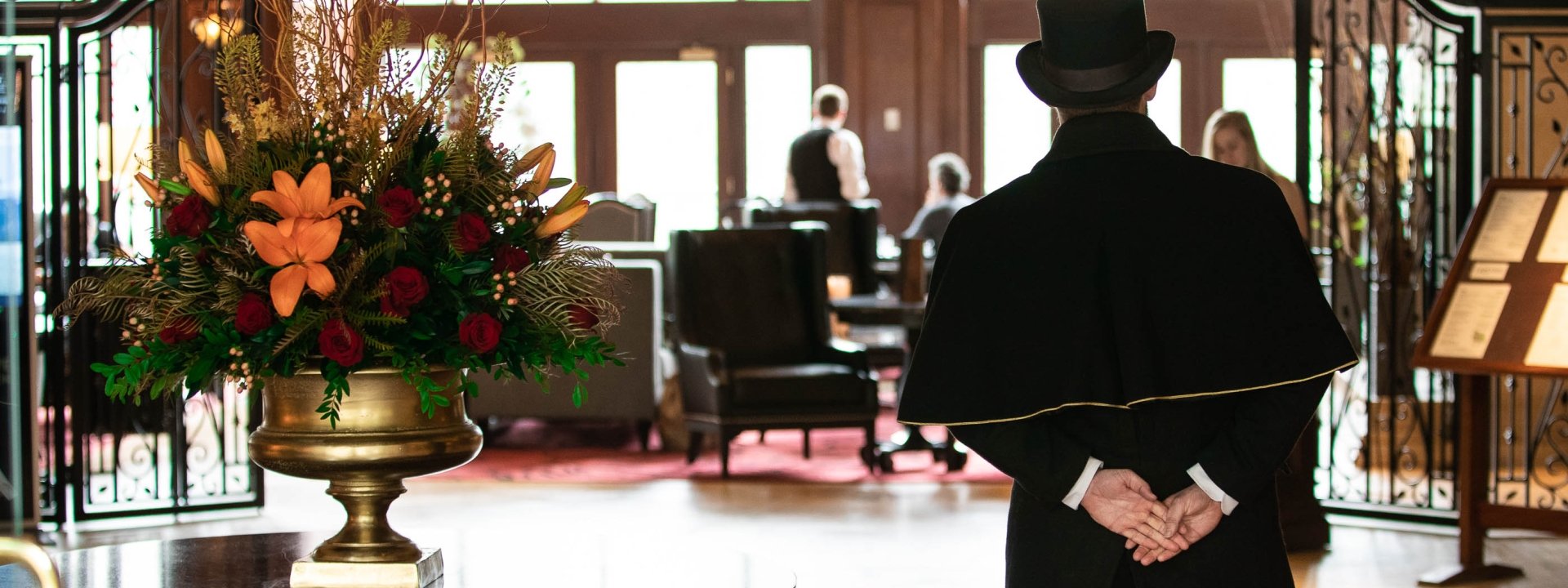 A man in a top hat standing with his arms to his back