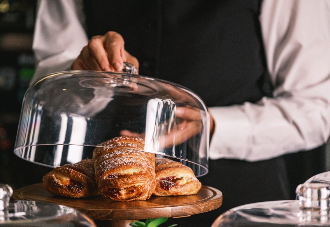 woman lifting lid on pastries