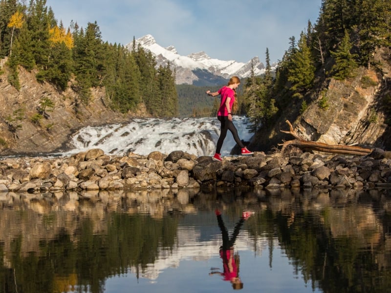 A girl walking by Bow Falls beside the Bow River in Banff