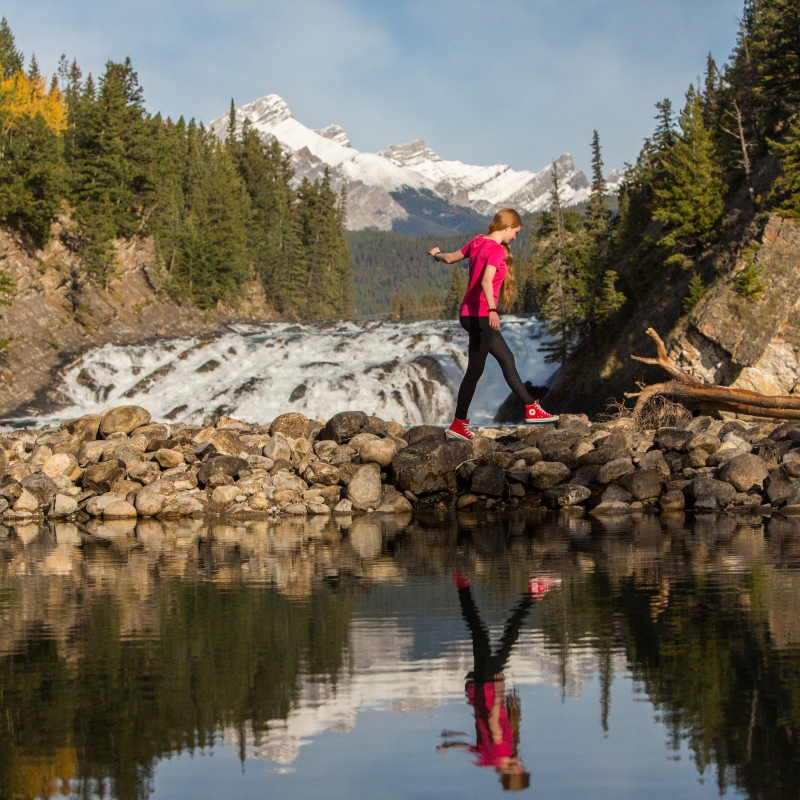 A girl walking by Bow Falls beside the Bow River in Banff