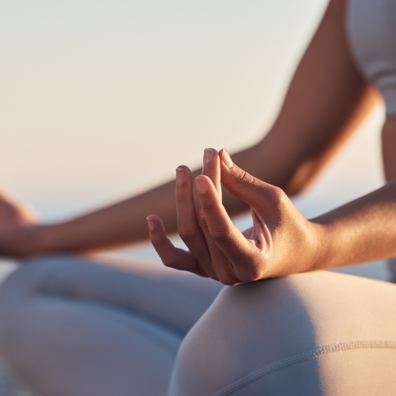 Woman, hands or lotus pose meditation on sunset beach, ocean or sea in mental health, mind training or chakra balance. Zoom, peace or zen yogi in calm mudra, relax yoga wellness or sunrise gratitude