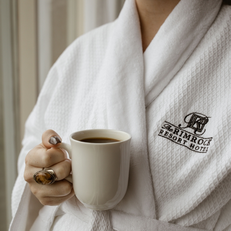 Women holding a cup of coffee wearing The Rimrock Resort Hotel