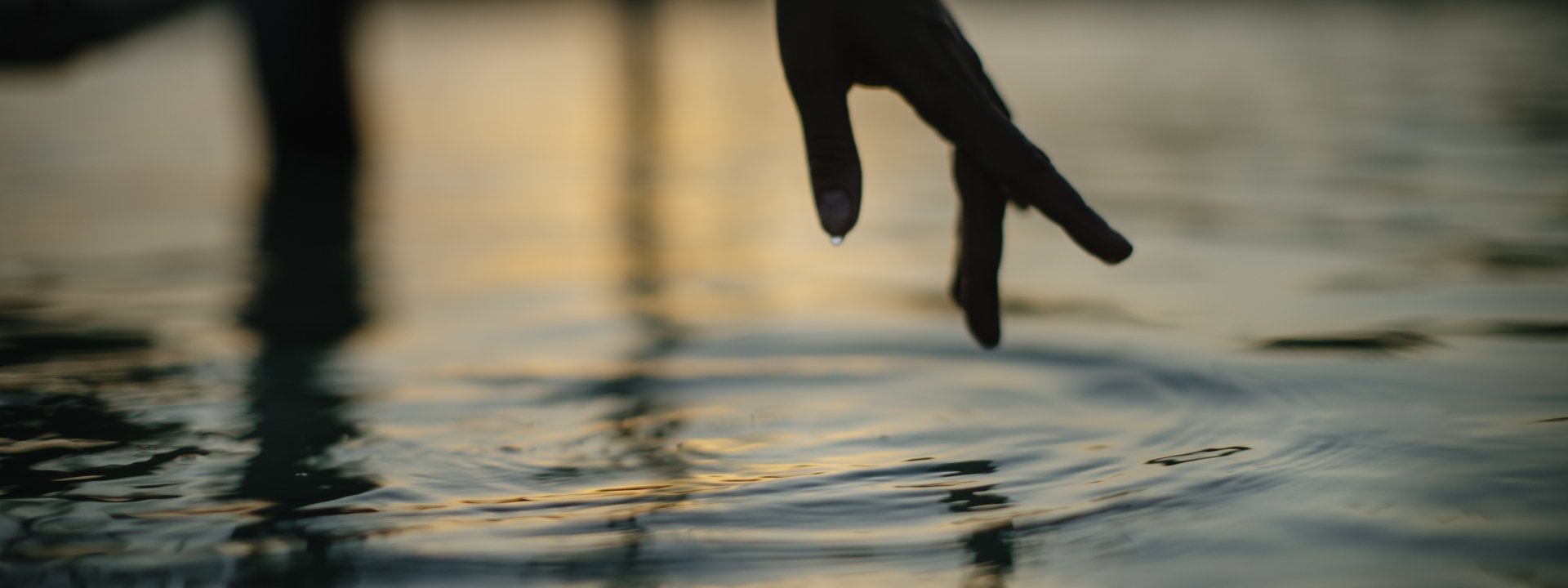 Finger dipping into water in a sacred moment of tranquility