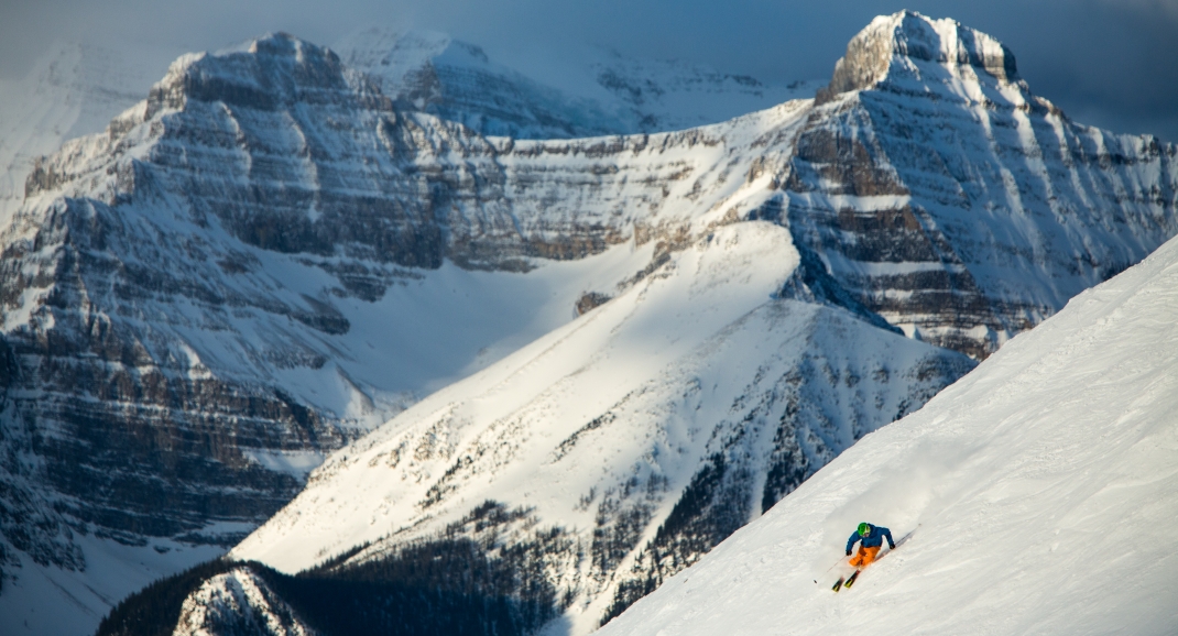Skier heading down the mountain with Banff mountains in the background