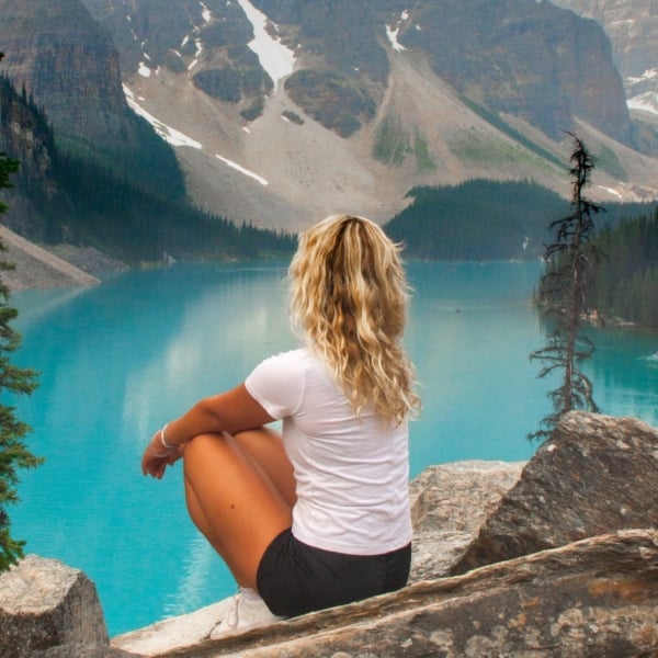 Woman sitting on the shores of Moraine Lake in Banff National Park.