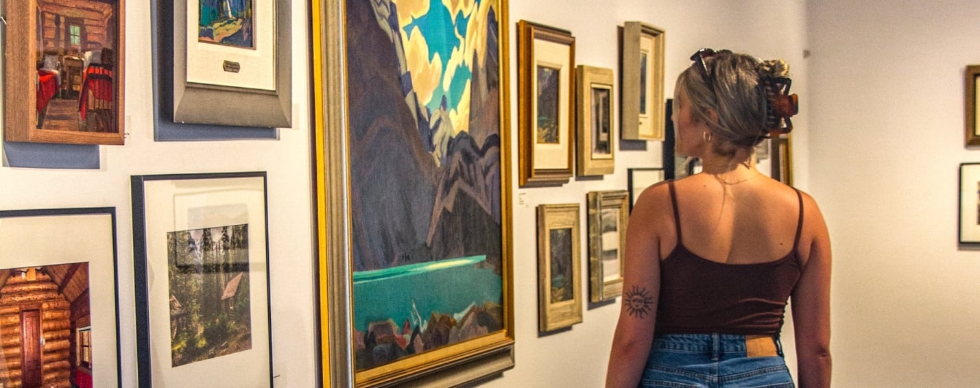woman looking at JH MacDonald paintings at the Whyte Museum
