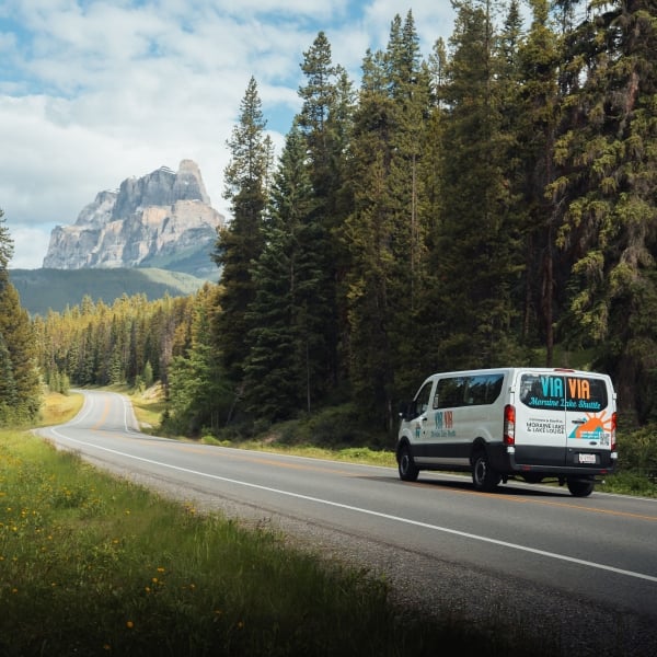 ViaVia Moraine Lake Shuttle driving down the road with mountains in the background
