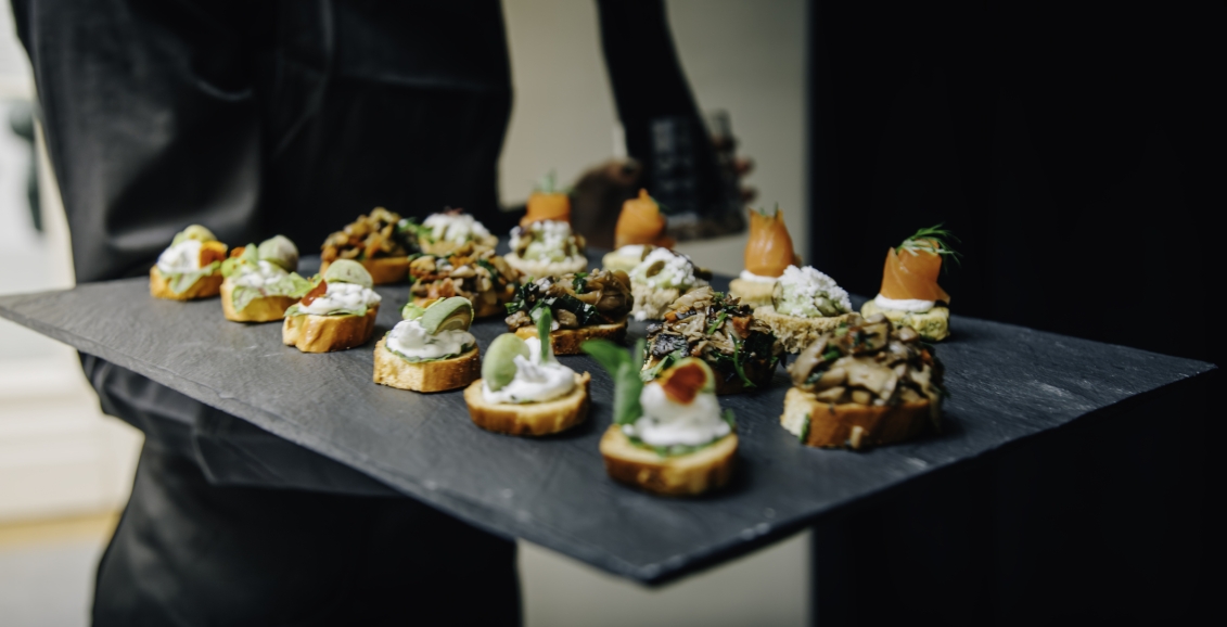 A server with a tray of hors d'oeuvres on a stone plate.