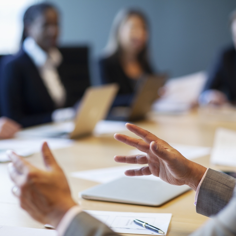 A group of people around a boardroom table discussing business in Waypoint Meeting Room at Rimrock Emblems Collection.