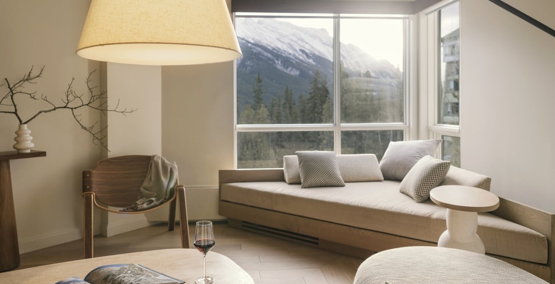 The living space of a one bedroom Suite at Rimrock Banff with comfortable seating at expansive valley views