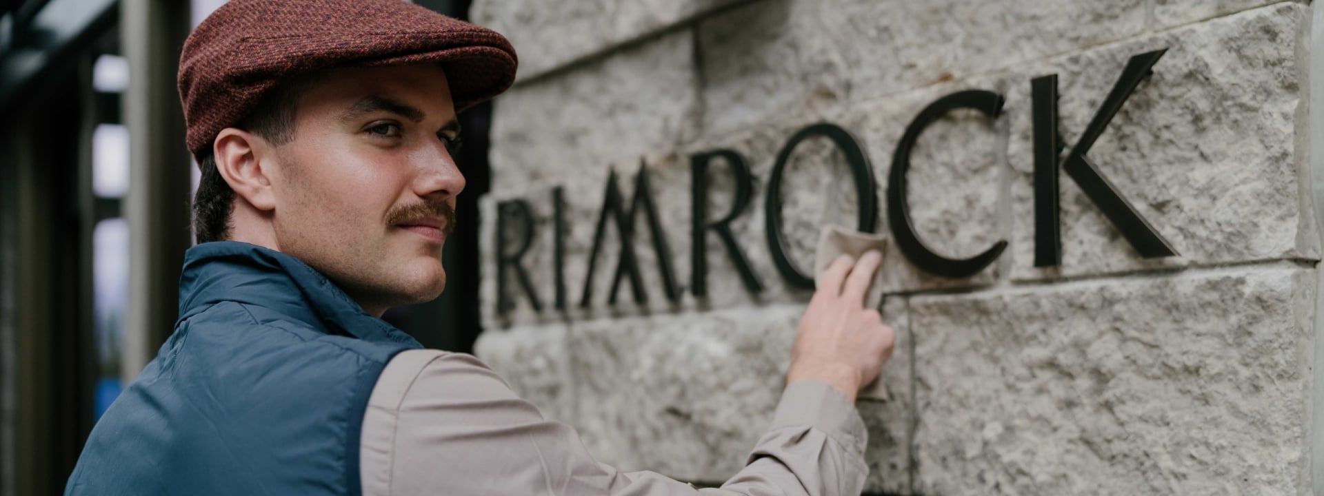 A bellman polishing the new Rimrock sign at Rimrock Banff, Emblems Collection